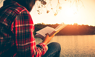 Una mujer leyendo frente a un lago