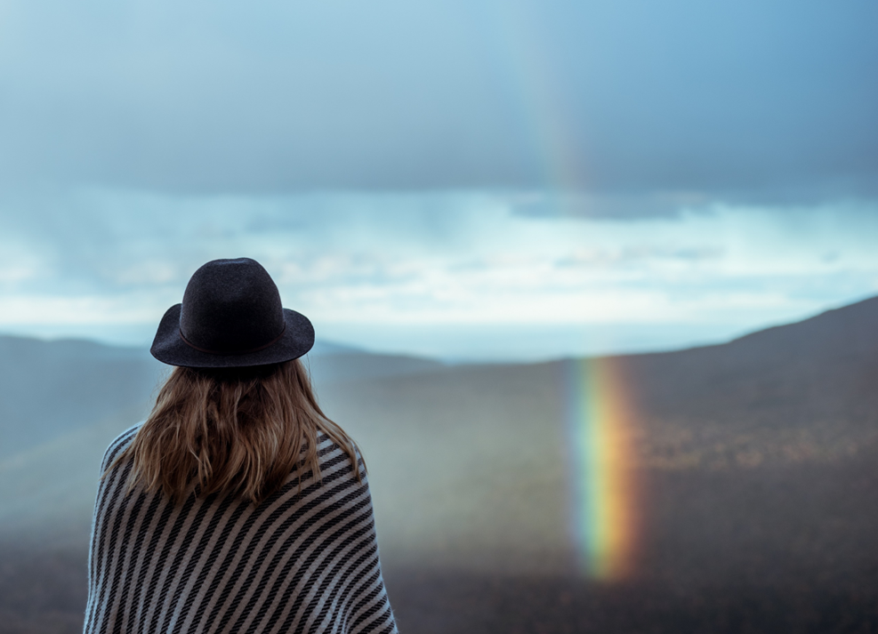 Mujer de espaldas con arcoiris de fondo