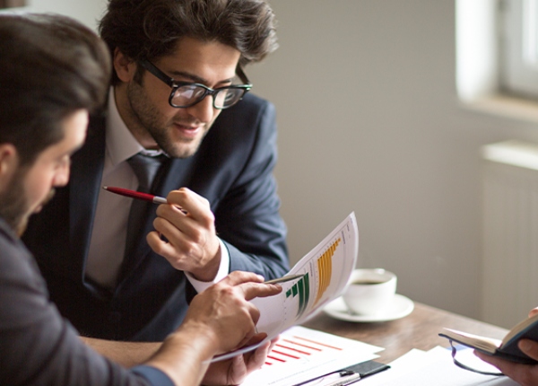 Jóvenes ejecutivos revisando un informe financiero de manera distendida