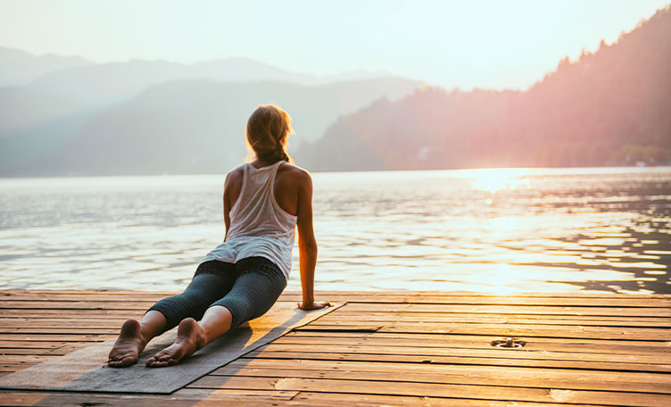 Una mujer haciendo yoga frente a un lago